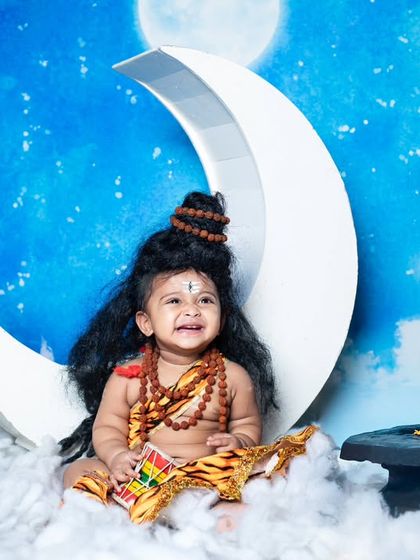 A joyful little Shiva, laughing and playing with his damaru on a crescent moon.