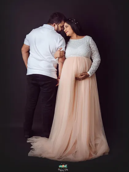 A tender moment captured against a classic dark backdrop. This pose emphasizes their connection and the beautiful silhouette of the baby bump.
