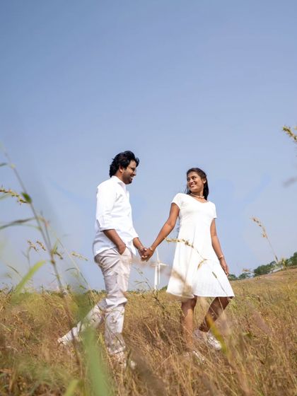 A beautiful shot of a couple walking hand-in-hand through a field, capturing the beginning of their journey together.