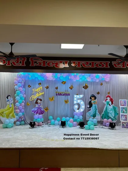 A princess-themed stage decoration featuring an L-shaped balloon arch and cutouts of various Disney princesses.