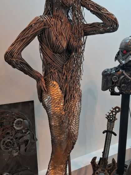 A close-up of the mermaid sculpture next to a stormtrooper bust, highlighting the diverse themes in metal art.