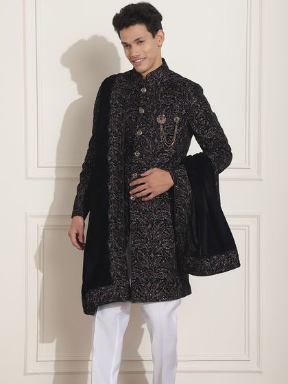 A black Indo-Western achkan with a velvet stole, showcasing a look of pure sophistication. The brooch adds a touch of classic royalty.