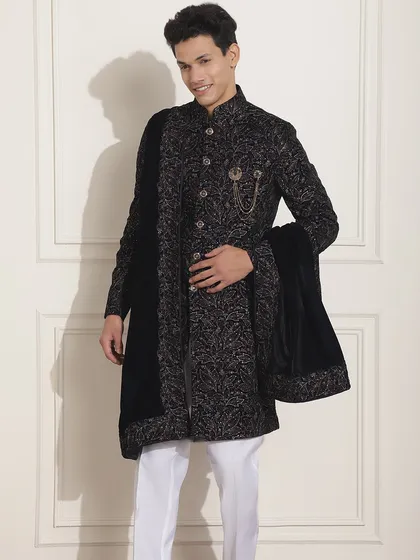 A black patterned Indo-Western sherwani, paired with a velvet stole and a statement brooch, is a classic choice for any wedding event. It's lightweight, classy, and tailored by my experienced craftsmen.