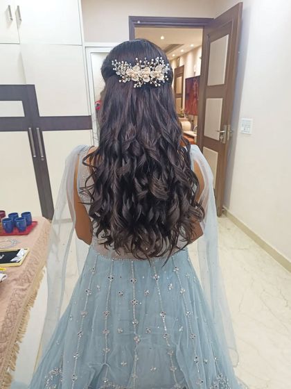 A half-up hairstyle with soft waves, accessorized with a beautiful pearl and crystal hairpiece. This is a perfect look for a Roka or engagement bride.