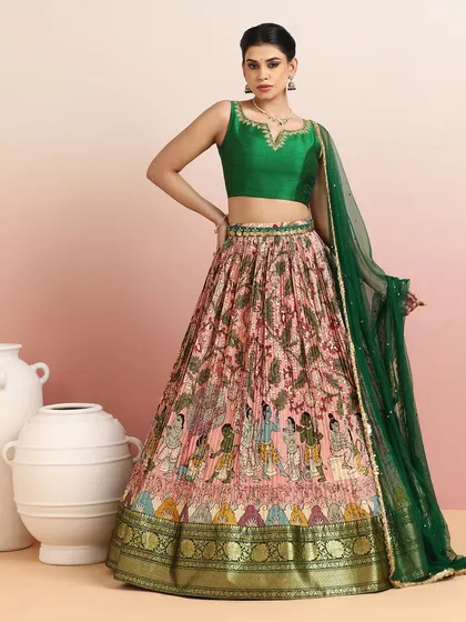 This unique lehenga features a skirt with intricate mythological prints, paired with a rich emerald green blouse and a sheer dupatta. It is a piece of wearable art that tells a story.