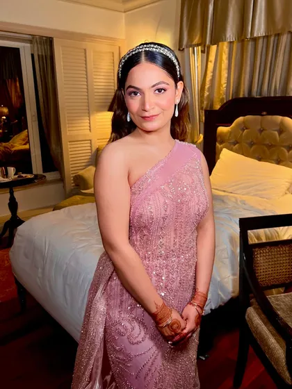 The full look in her hotel room, ready for the sangeet. The pink gown, wavy hair, and glowing makeup come together for a perfect princess moment.