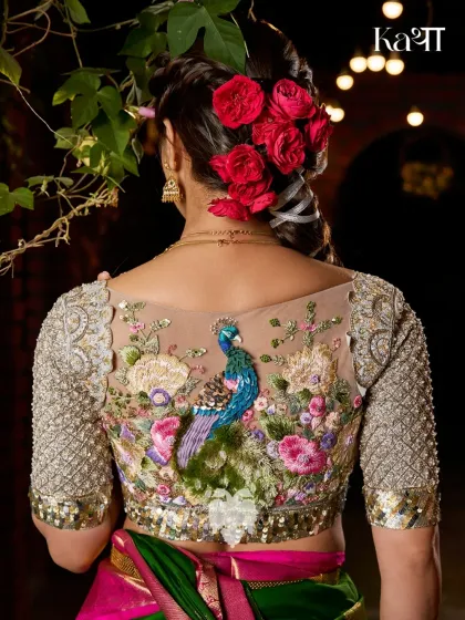 This is the Nemali Vanam blouse, a piece that captures the poetry of a peacock's dance. The back is set against a sheer base, allowing the intricate hand embroidery of lush florals and a regal peacock to become the centerpiece. The sleeves are embellished with katdana detailing, echoing the artistry of temple architecture.