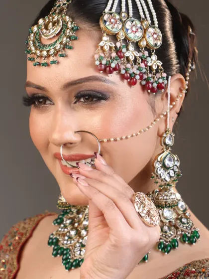 A close-up of the bride's stunning jewelry and flawless makeup. The details, from the nath to the jhumkas, are perfectly complemented by her look.