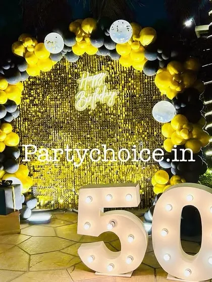 A fun and glamorous poolside setup for a 50th birthday. The gold sequin backdrop, black and yellow balloon arch, and large light-up '50' create a celebratory party vibe.