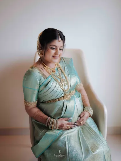 An elegant solo maternity portrait showcasing the mother's radiant glow. The simplicity of the setting puts all the focus on her, her beautiful silk saree, and the precious life she is carrying.