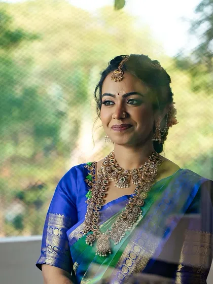 A lovely shot through a window, adding a soft, dreamy quality to the bride's look. Her radiant smile is the centerpiece.