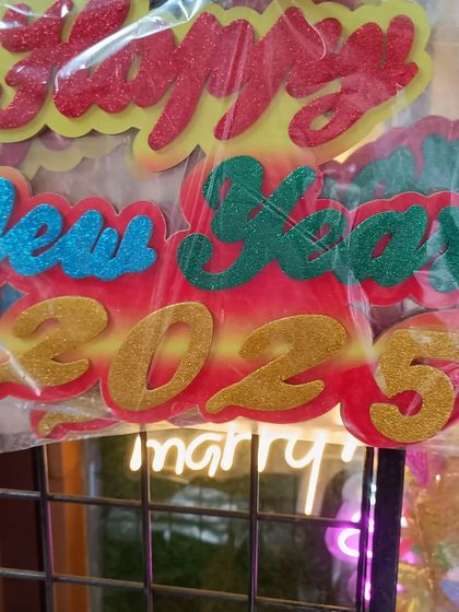 A sparkly 'Happy New Year 2025' cutout decoration. This glittery sign is perfect for hanging on a wall or as part of a photo booth backdrop.