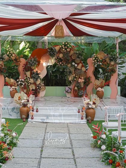 A full view of a sustainable wedding ceremony with a terracotta and boho theme. The aisle is lined with floral arrangements leading to a unique, artistic stage.