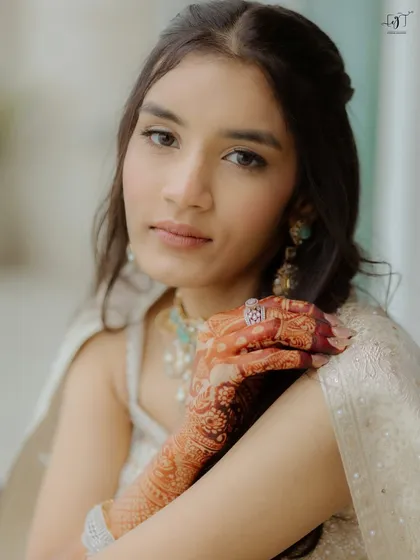 A close-up of Moksha's natural beauty. The makeup is minimal and soft, enhancing her features and letting her stunning jewelry and henna stand out.