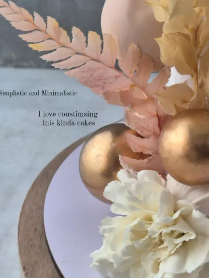 A detail shot of the engagement cake, focusing on the delicate dried florals, carnations, and gold-painted spheres.