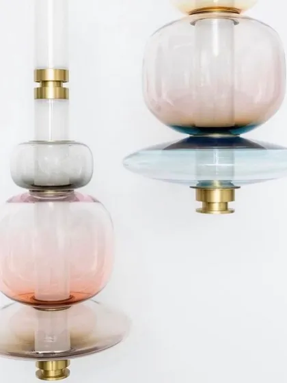 A detailed shot of two Luna pendants, revealing the beautiful gradient of colors in the hand-blown glass and the precision of the brass hardware.