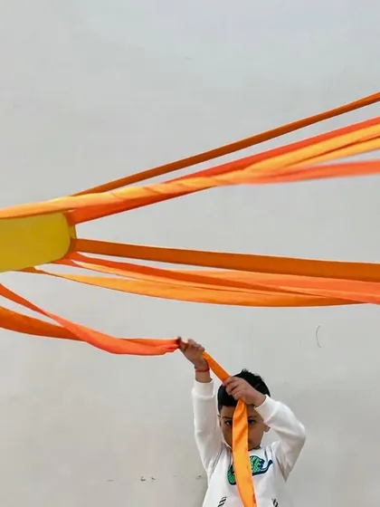 Three young students proudly hold up the rays of a sun prop. Our classes often involve group activities that foster a sense of community and shared accomplishment.