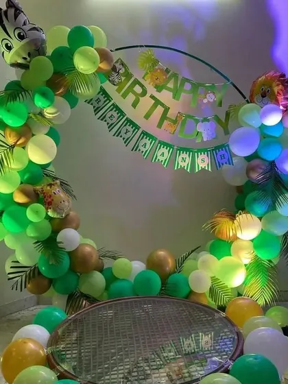 A jungle-themed birthday party with a circular balloon arch, animal foils, and a 'Happy Birthday' banner.