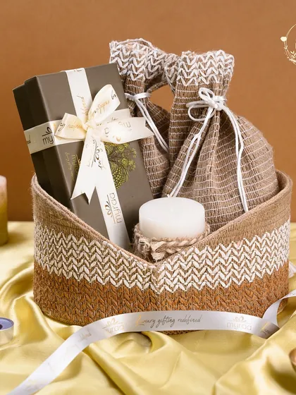 Simple, elegant, and full of warmth. This cozy basket hamper includes a box of gourmet treats, scented candles, and jute potlis, making it a heartfelt and beautiful gift for the festive season.