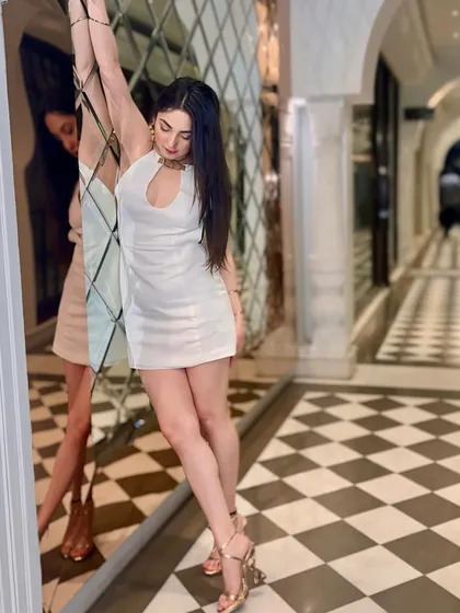 A dramatic pose against a mirrored wall, showcasing the elegant and playful side of this white party dress.