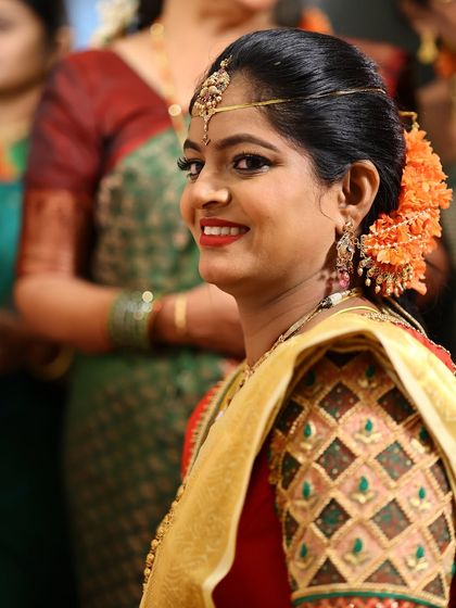 A candid smile that says it all. This bride's happy glance shows her confidence and joy. Her classic South Indian makeup with a red lip and simple hair accessories creates a look of timeless elegance.