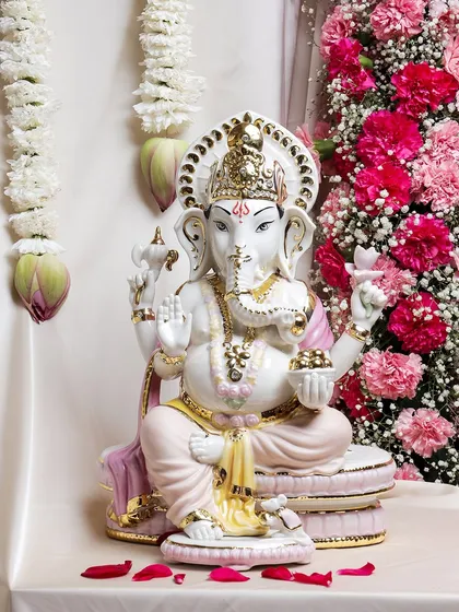 This large, hand-painted porcelain Ganesha idol is adorned with delicate pink and gold accents. It's a statement piece that combines traditional iconography with a soft, modern color palette.