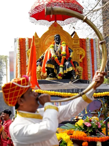 The reverence and grandeur of a cultural procession. Here, a man blows a traditional tutari horn, heralding the arrival of the Chhatrapati Shivaji Maharaj float during a vibrant Shobha Yatra.