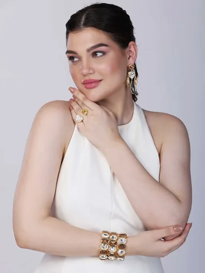 A model gracefully poses to feature contemporary earrings, a ring, and a statement cuff. The soft side glance and clean composition create an elegant and sophisticated look for a fashion jewellery lookbook.