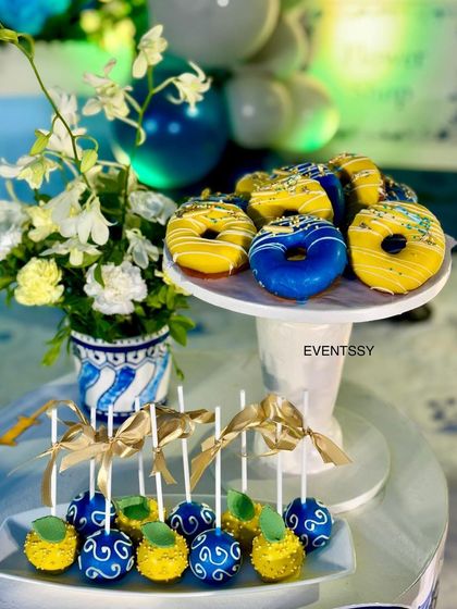 Themed donuts and cake pops in vibrant blue and yellow, matching the party's color scheme.
