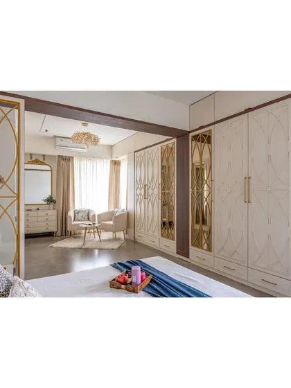 A full view of the custom floor-to-ceiling wardrobes with intricate gold and mirror detailing. This design provides ample storage while serving as a stunning feature wall.