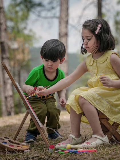A brother and sister collaborate on a painting during a creative and fun outdoor art-themed shoot.