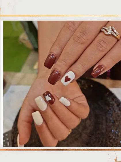 A sweet and romantic set perfect for Valentine's Day. It features a mix of brown, white, and cream nails with cute, hand-painted heart details.
