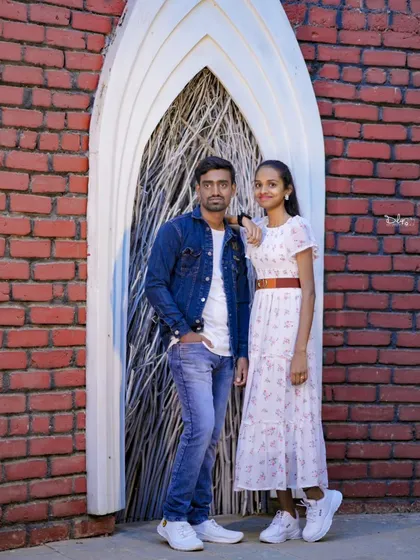 A stylish pose against a brick wall. The couple's casual denim and white outfits create a classic, cool look.