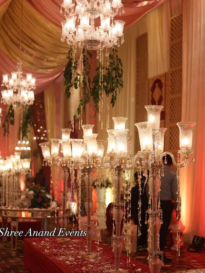 Tall, elegant crystal candelabras with multiple lamps, creating a warm and romantic glow along the event pathways.
