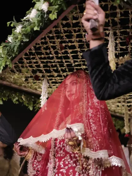 The bride's grand entrance under a floral canopy, or 'phoolon ki chadar'. This is a classic and beautiful moment in many Indian weddings, captured here with a focus on her serene expression.