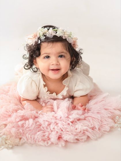 The sweetest smile from an eleven-month-old baby. Lying on a fluffy pink rug, she looks so happy and content.
