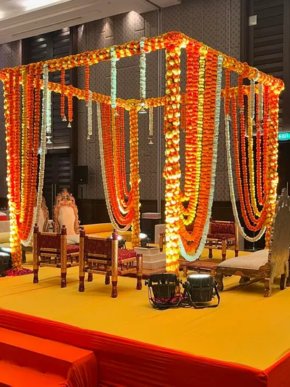 The beauty of a traditional wedding is timeless. This Vidhi Mandap is heavily decorated with strings of orange and yellow marigolds, creating a vibrant and auspicious setting for a Ganesh Puja or wedding ceremony.