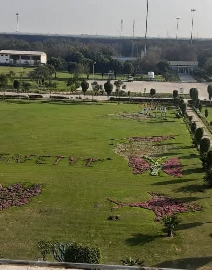 A wide, elevated view of the entire landscaped area at the power plant, showing the scale of the lawns, pathways, and intricate flower designs.