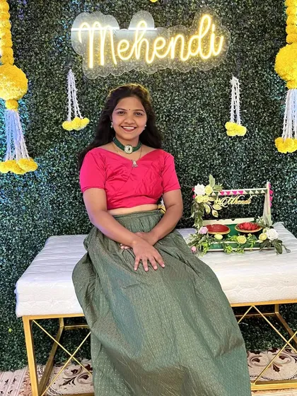 Our popular Mehendi setup featuring a lush green wall, a comfortable white bench for the bride, and a bright 'Mehendi' neon sign.