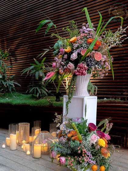 A grand floral installation for a sundowner event, surrounded by candles, creating a dramatic and romantic focal point.