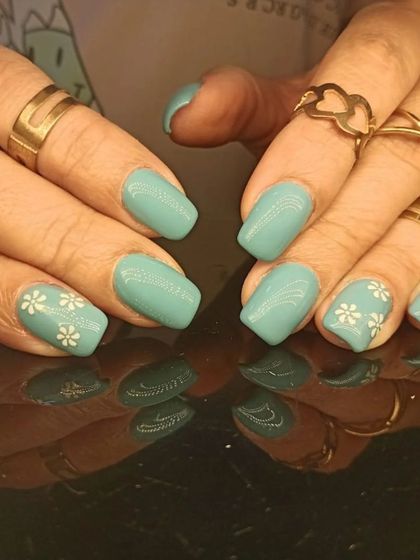 A simple and sweet teal manicure with delicate white daisy accents.