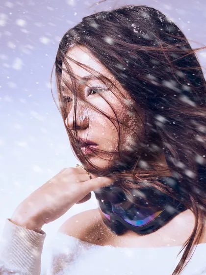 The feeling of a blizzard captured in a single frame. The wind-swept hair and frosted makeup effect create a sense of beautiful, chaotic stillness.