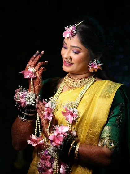 A full view of this bride's Haldi attire. The yellow saree and green blouse are beautifully accessorized with custom floral jewelry for her hands, ears, and hair.