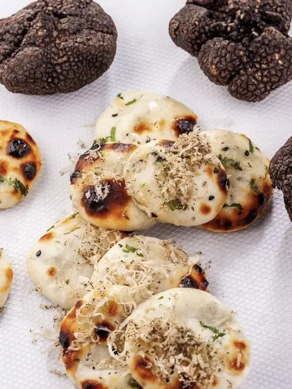 We take our breads seriously. Here, our fluffy mini naans are generously topped with freshly shaved black truffle, transforming a humble staple into a moment of pure luxury.