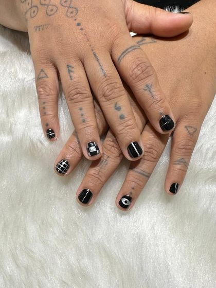 Not your basic black manicure. This unisex set on short nails features a mix of hand-painted geometric patterns, including grids, stripes, and an evil eye design for an edgy, punk-inspired look.