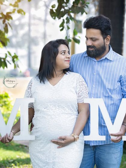 A creative maternity shot where the couple holds large letters spelling 'MOM', with the 'O' perfectly framing the baby bump.