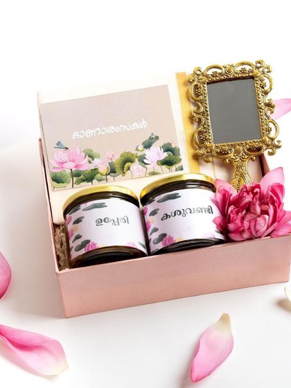 The 'Thamara' hamper unboxed, with its contents displayed. The simple combination of traditional snacks and a beautiful valkannadi makes for a graceful and thoughtful gift.