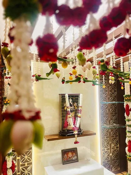 Another view of the pooja room decorated with hanging floral parrots and lotus buds. These traditional elements are believed to bring prosperity and positivity to a new home.