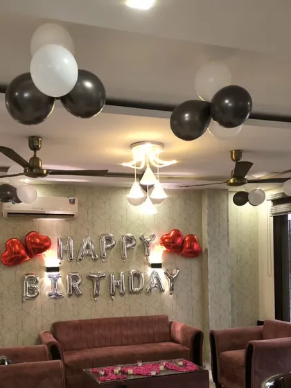 The birthday living room setup, showing the silver foil 'Happy Birthday' banner flanked by red heart balloons.