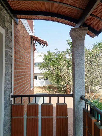 A balcony view from the Hemavathi and Hareesh residence, featuring a curved terracotta tile roof and a parapet wall made of hollow clay blocks.
